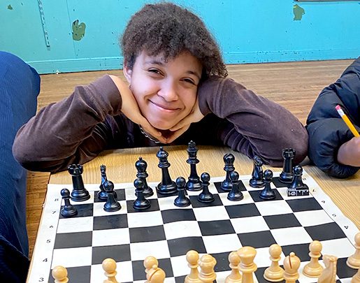 Beautiful girl smiling with chess board in front of her