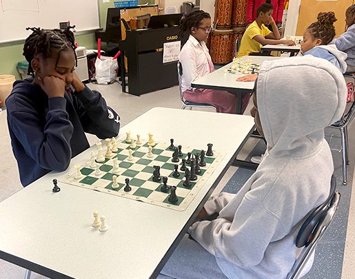 Two youn kids playing chess in a chess program